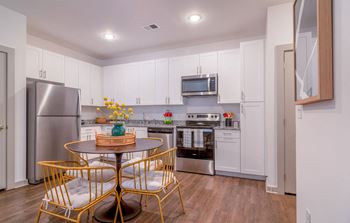 A kitchen with white cabinets and a table and chairs